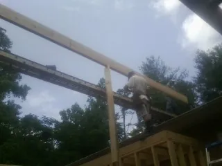 Carpenter setting a ridge beam over a new addition frame — Ice Dam Removal by Roofing Brothers in East Montpelier