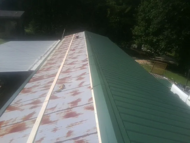 Old rusted panels beside newly installed green metal roofing — Wind Damage Roof Repair by Roofing Brothers in East Montpelier
