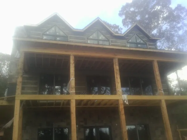 Dormers and porch framing on a large log home under construction — Roof Coating work by our crew in East Montpelier