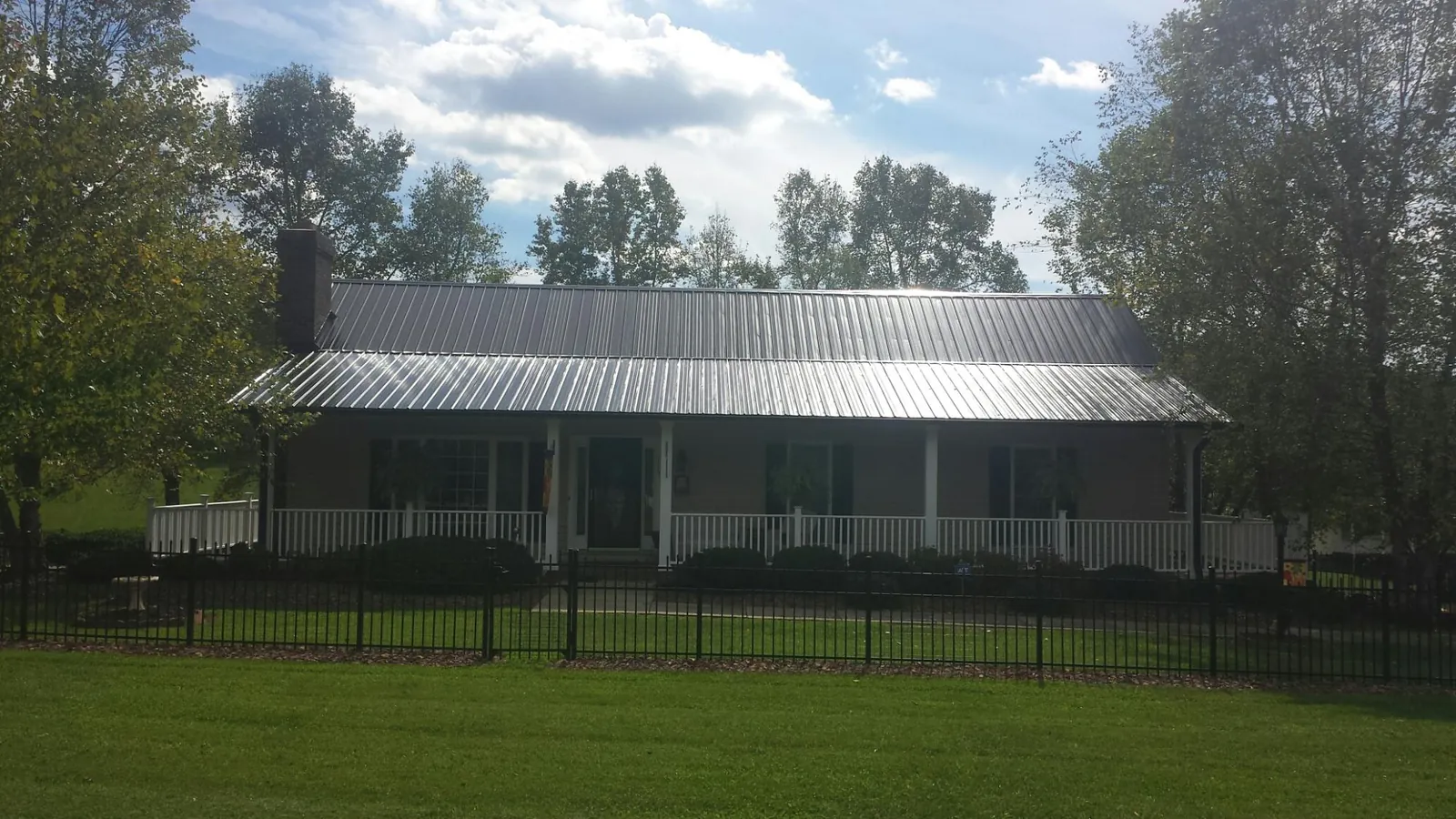 Gray metal roof on a brick ranch with a full width front porch — Gutter Guard Installation work by our crew in East Montpelier