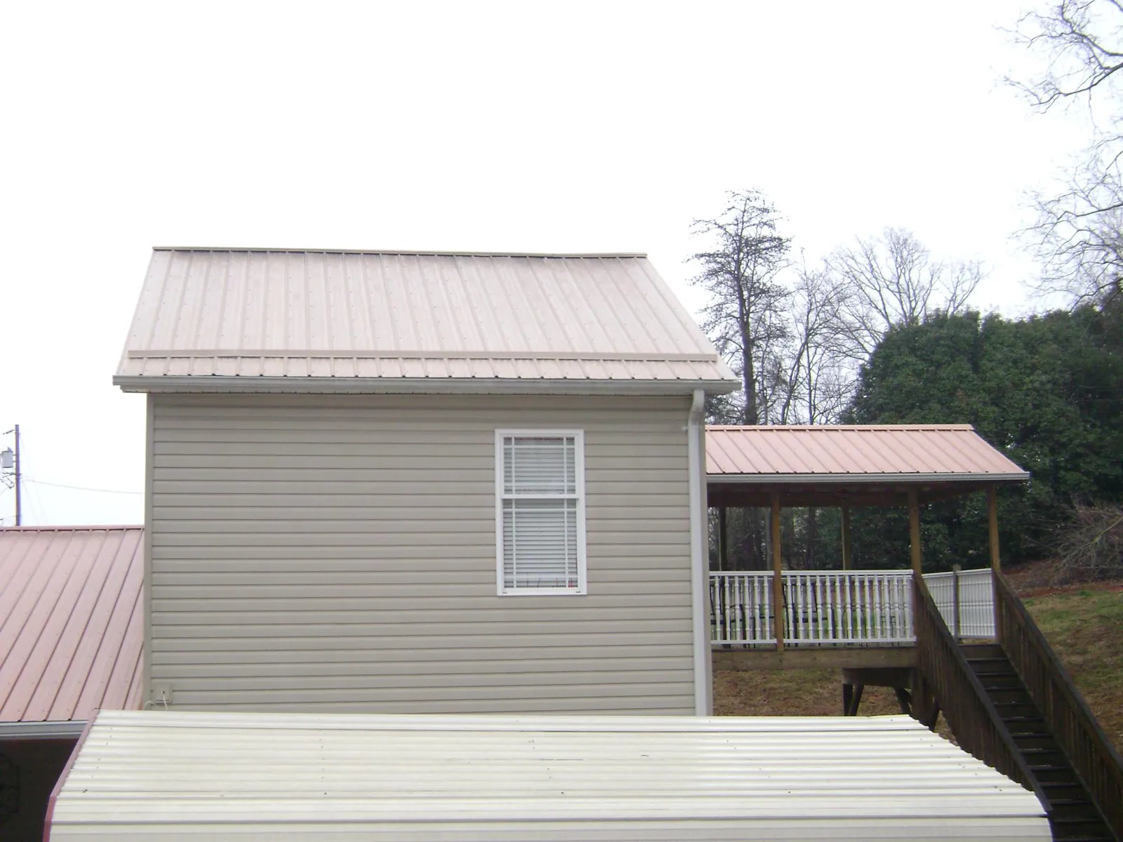 Tan metal roofs on a two story addition and attached porch, from a Roof Replacement job in East Montpelier